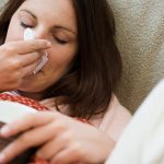 Woman with tissue and hot drink